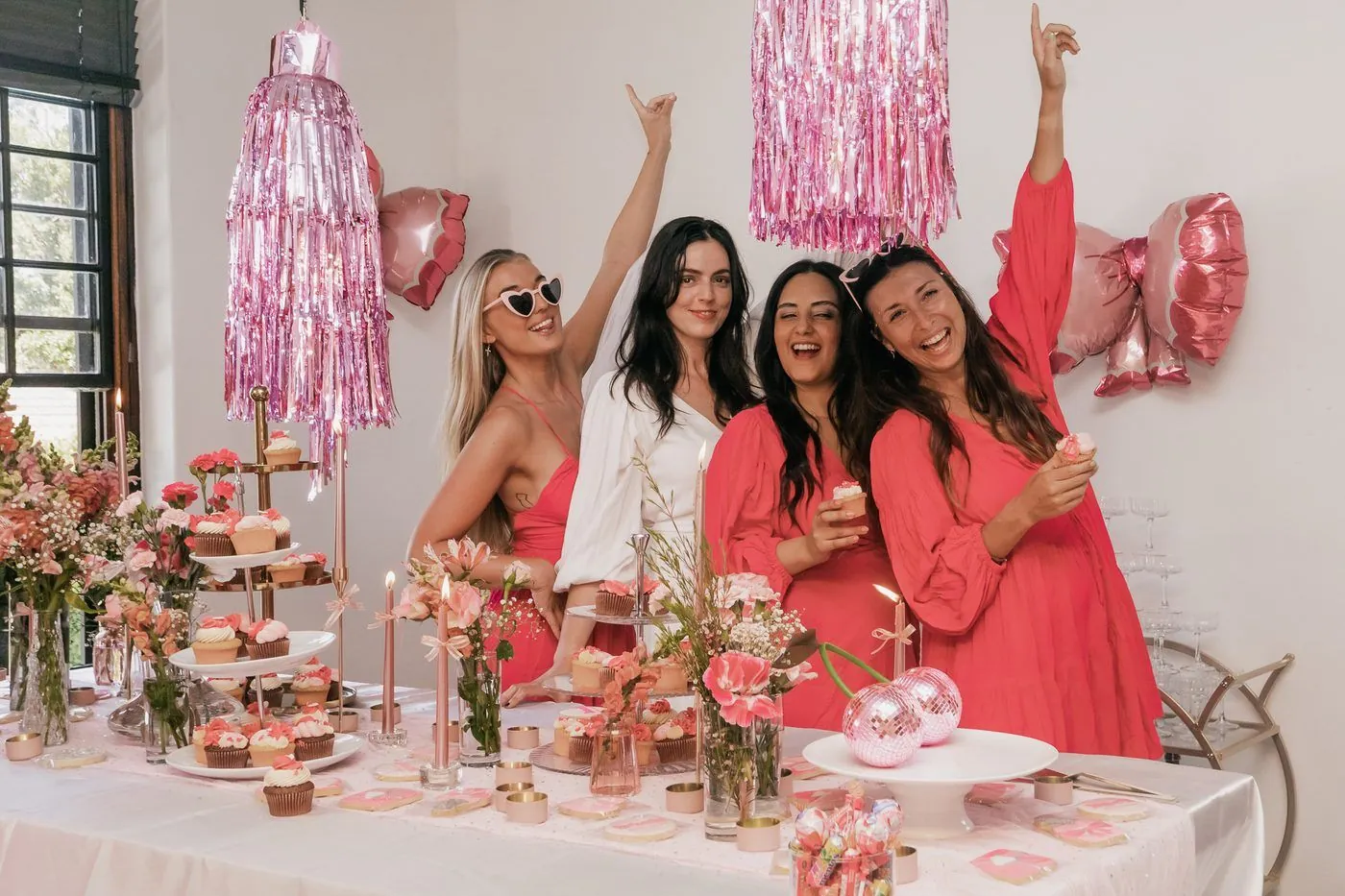 Friends celebrating around a styled pink dessert table with cupcakes, florals and balloons at a Cape Town bachelorette